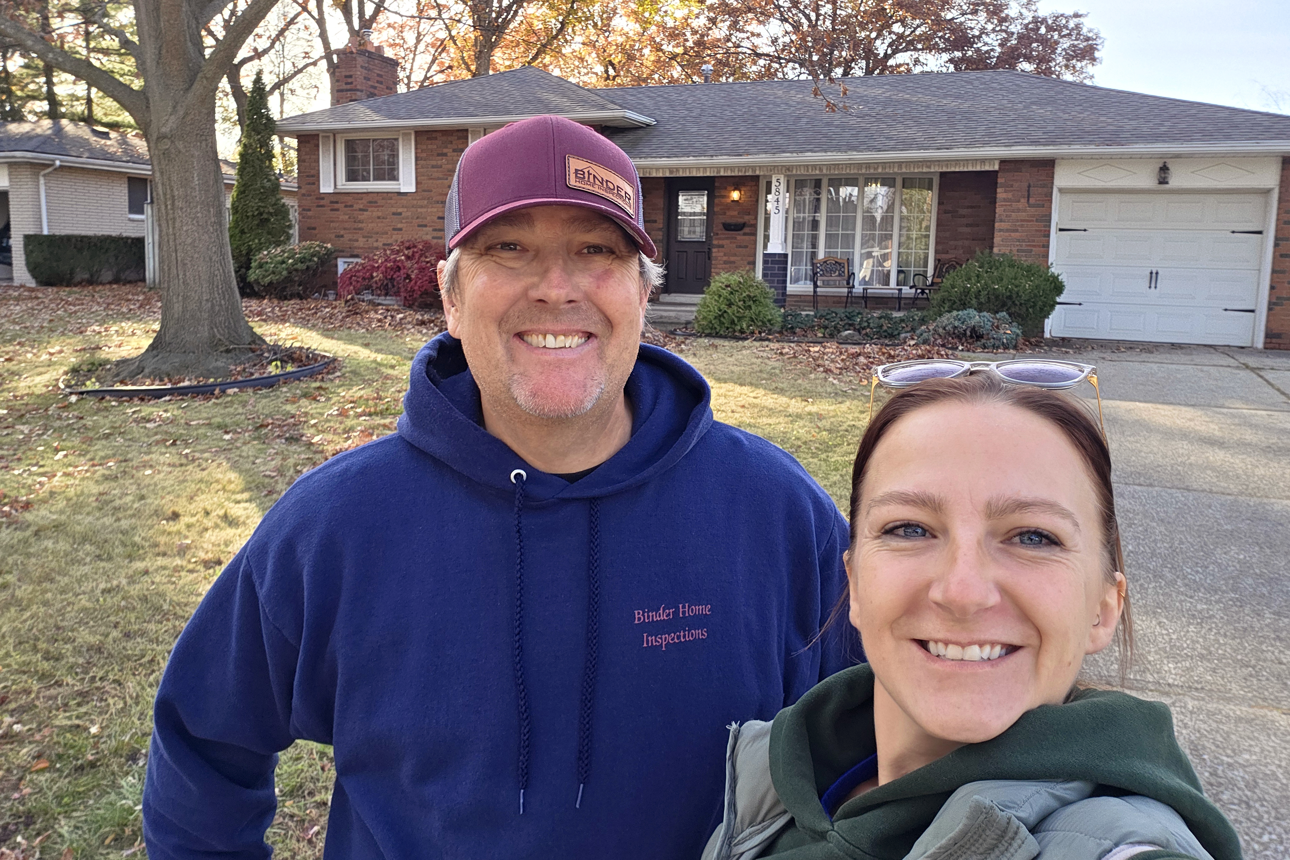 John Binder and Larissa McMullin, Certified Home Inspectors, standing in front of a house